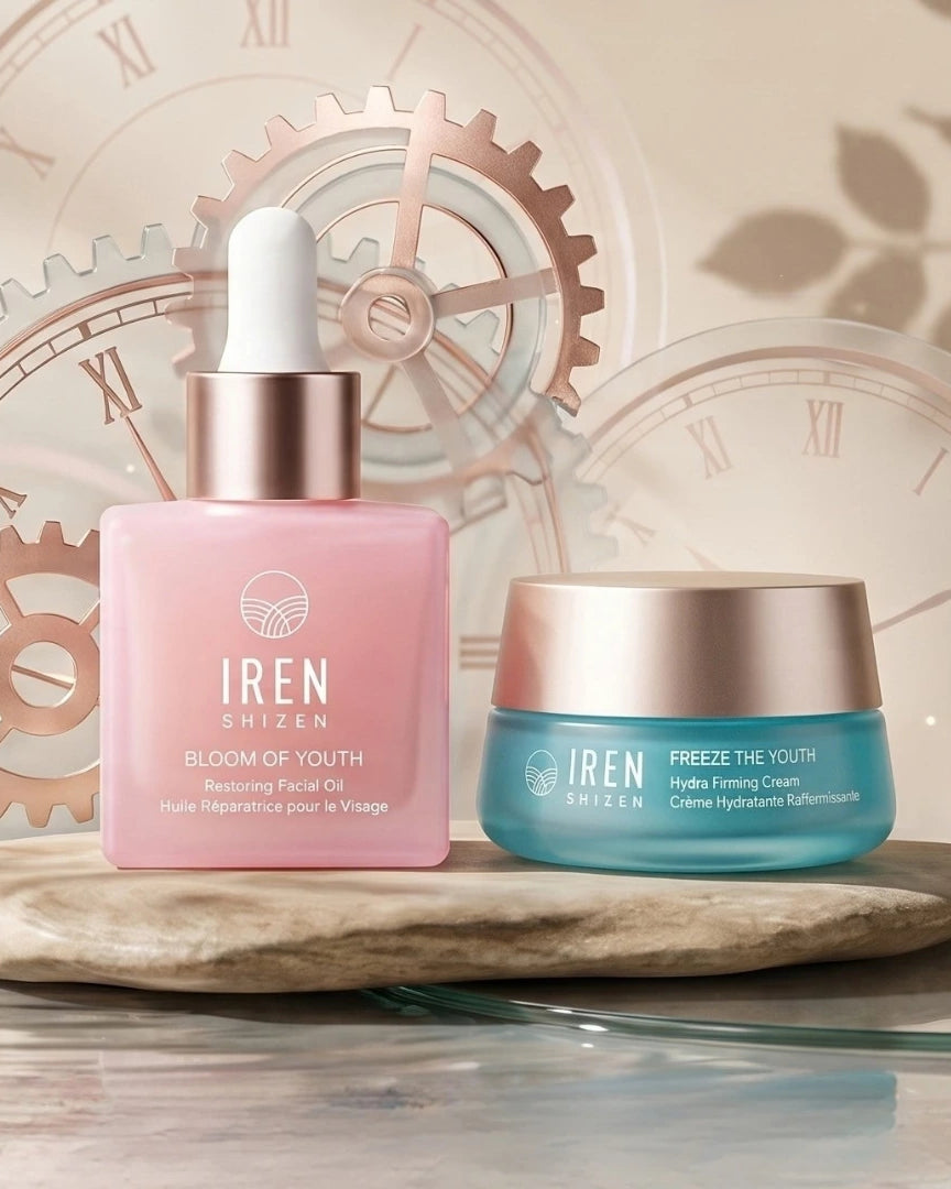 A pink glass dropper bottle and a blue jar from the Fast Bundle TIME REBOUND Lift and Firm Kit sit on a stone-like platform against a background of clockwork gears.