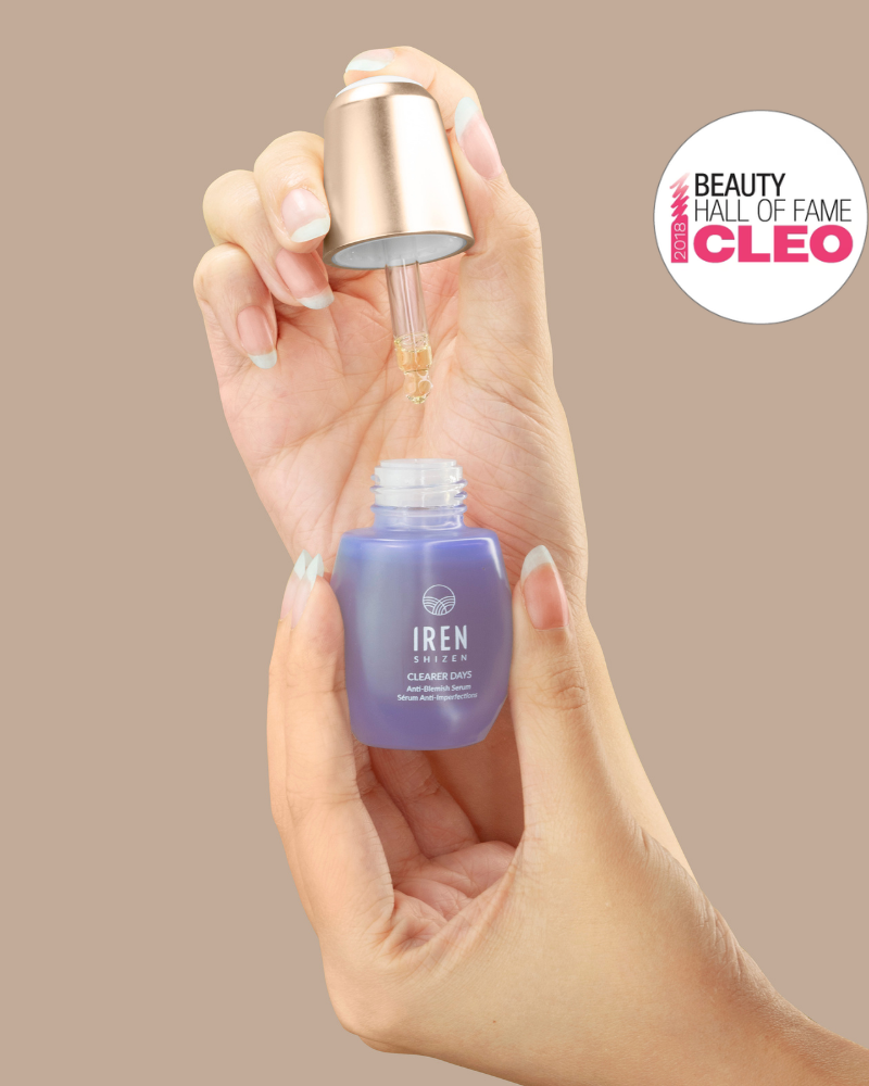 A hand holds a dropper above a blue FRESH AND CLEAR Cleansing Kit bottle from Fast Bundle, with a Beauty Hall of Fame award badge in the background—perfect for your skincare routine.