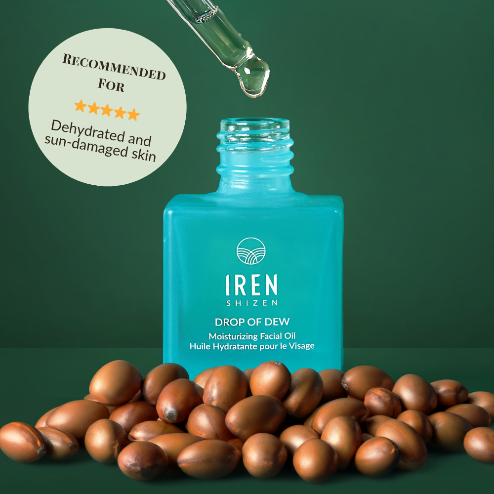 A blue bottle of IREN Shizen DROP OF DEW Moisturizing Facial Oil with a dropper above and argan nuts in front; the label highlights its recommendation for dehydrated and sun-damaged skin, supporting effective skin barrier repair.