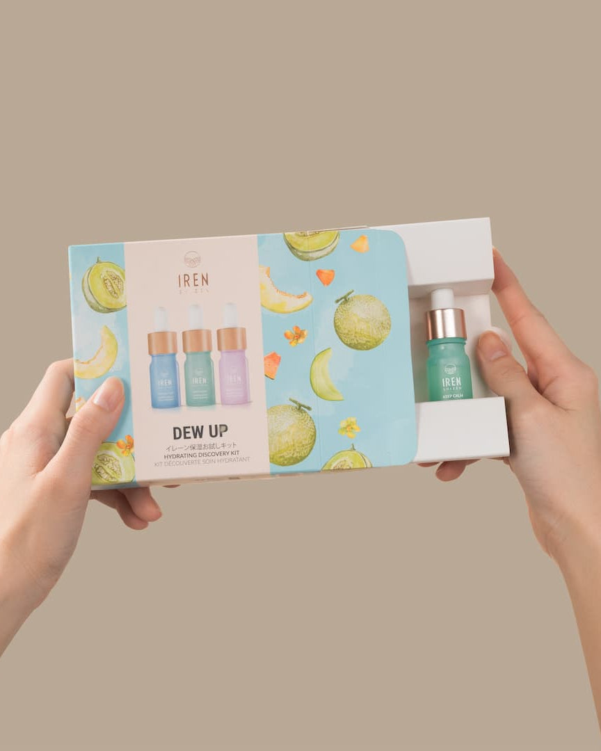 A hand holding a box with IREN Shizen's DEW UP Hydrating Discovery Kit, creating a skincare trio that provides moisture-rich hydration.