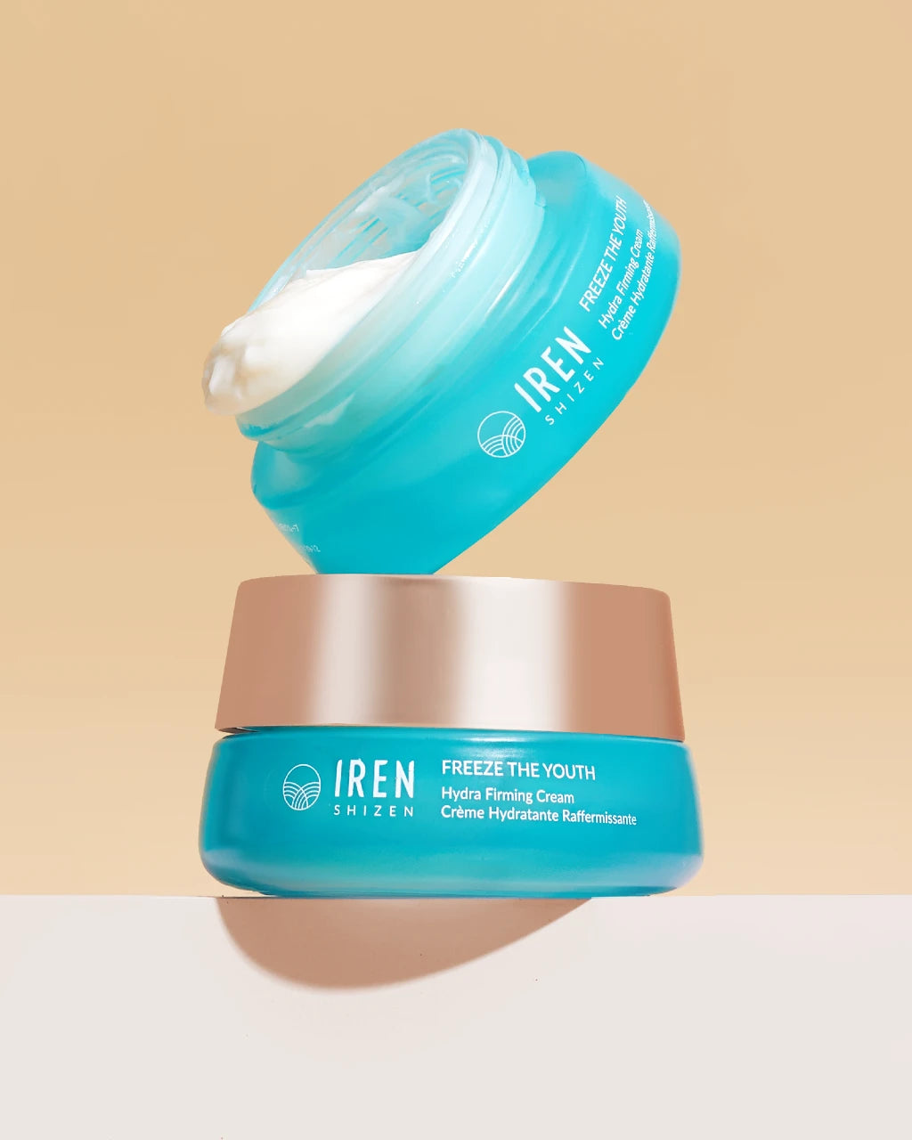 Two stacked teal jars of the TIME REBOUND Lift and Firm Kit, with the top jar open to reveal white anti-aging cream inside.