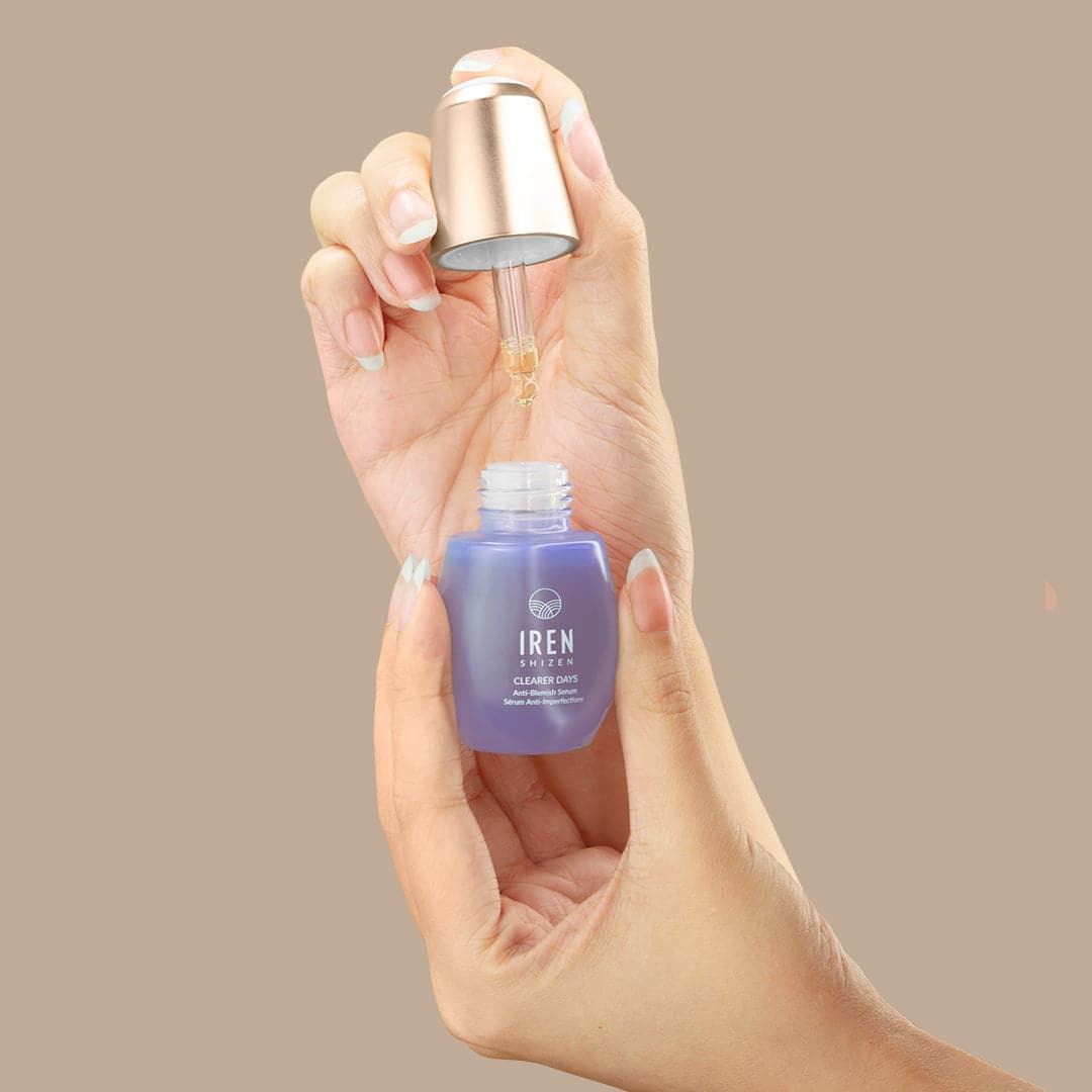 A hand holding a bottle of customised CLEARER DAYS Anti-Blemish Serum by IREN Shizen, a Japanese skincare brand inspired by onsen skincare, containing a blue liquid. #all-groups