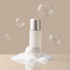 A bottle labeled "IREN Shizen" stands on a mound of foam with floating bubbles against a beige background, presenting the START AFRESH DAILY Enzyme Powder Wash, a gentle daily exfoliant rice enzyme cleanser.