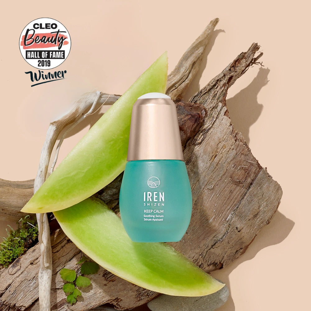 A bottle of IREN Shizen KEEP CALM Soothing Serum rests on wood with aloe vera slices, next to a Cleo Beauty Hall of Fame 2019 Winner badge—ideal for sensitive skin, eczema, and rosacea care.