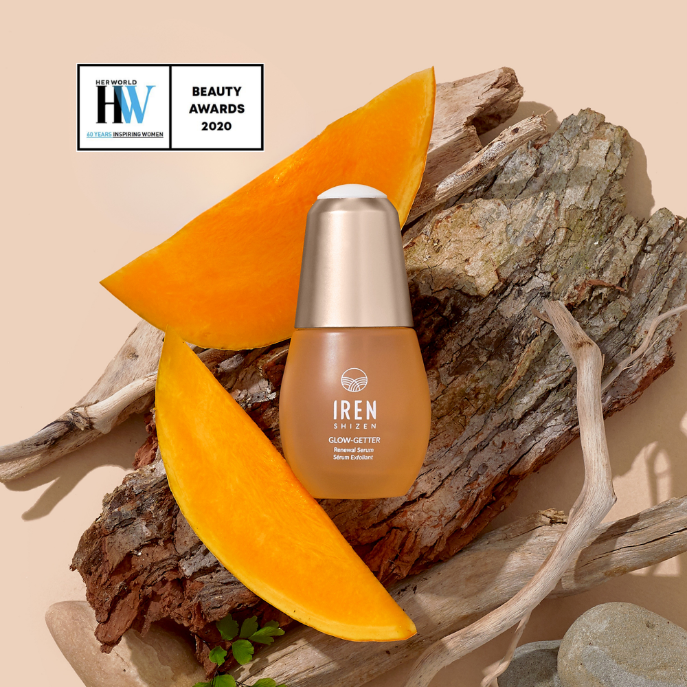 A bottle of IREN Shizen GLOW-GETTER Renewal Serum sits on wood with pumpkin slices. Formulated with Pumpkin Seed Extract for gentle exfoliation. A "Beauty Awards 2020" badge is shown in the top left corner.