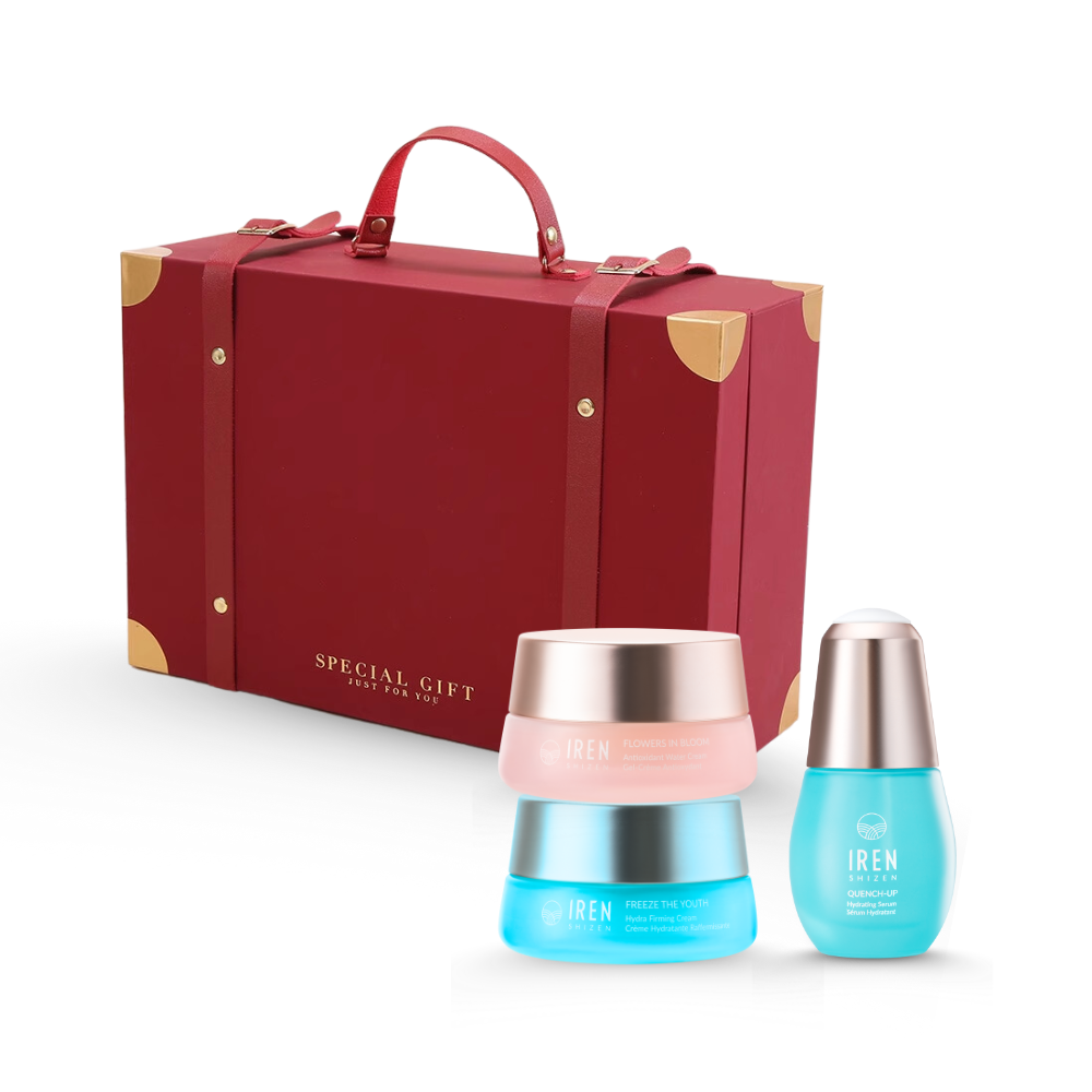 A festive red gift box with gold corners sits elegantly beside the CUSTOM XMAS For Beloved Ones Moisture Sandwich Gift Set by IREN Shizen. The lineup includes vibrant pink, blue, and turquoise containers, each housing a rejuvenating serum to pamper your skin.