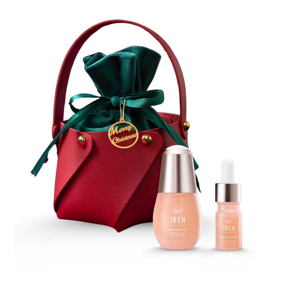 The CUSTOM XMAS For The Pals Serum Gift Set by IREN Shizen includes a red pouch with a green ribbon, featuring two skincare bottles—one with a pipette serum and the other with a cap. It comes with a gold "Merry Christmas" tag, making it the perfect gift box for the holiday season.