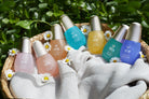 Assorted MOISTURE SANDWICH Skincare Kit bottles from IREN Shizen, including the Hydra Firming Cream, arranged neatly on a wicker basket amidst green foliage and daisies.