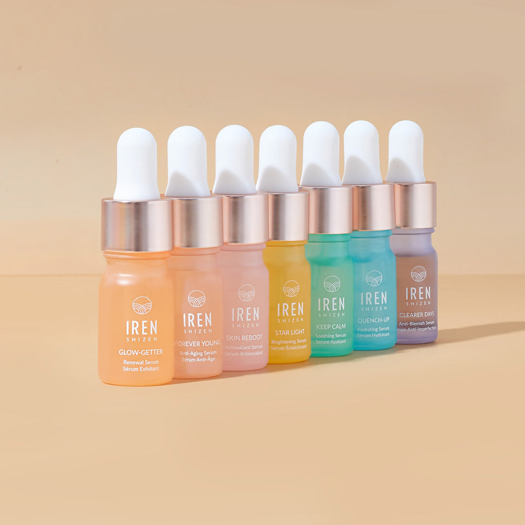 A set of Japanese skincare CLEAR UP Anti-Blemish Discovery Kits by IREN Shizen featuring different colored liquids on a beige background.