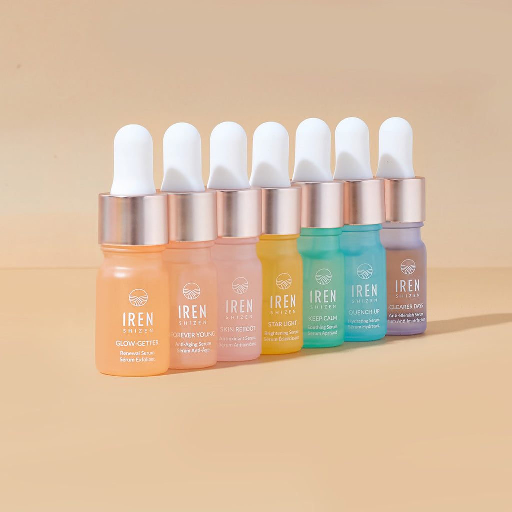A set of Japanese skincare CLEAR UP Anti-Blemish Discovery Kits by IREN Shizen featuring different colored liquids on a beige background.