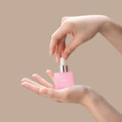 Someone holds a pink BLOOM OF YOUTH Restoring Facial Oil bottle from IREN Shizen in one hand and uses the dropper with the other against a beige background, showcasing skin barrier repair in their skincare routine.
#all-groups