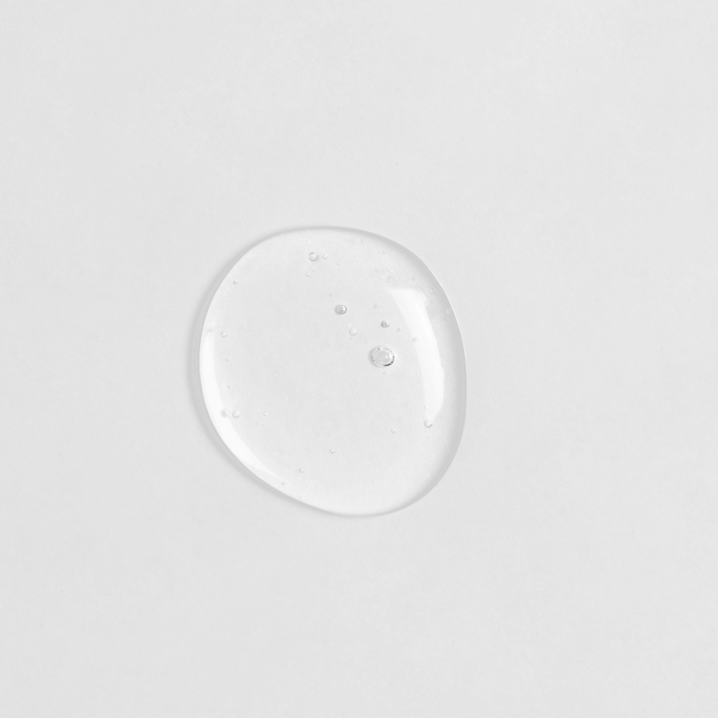 A small drop of custom skincare CLEAR UP Anti-Blemish Discovery Kit by IREN Shizen on a white surface.