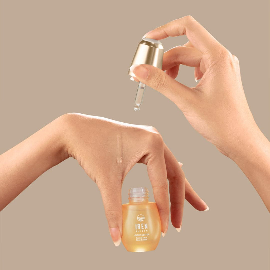 A woman's hand is holding a customised bottle of IREN Shizen GLOW-GETTER Renewal Serum.