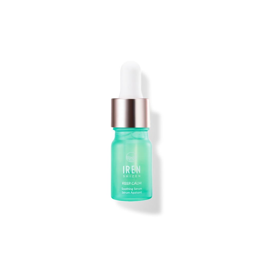 A green bottle of KEEP CALM Soothing Serum with a white lid on a black background by IREN Shizen.